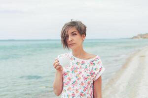 Beautiful woman relax during exotic vacation on the beach enjoying sweet coffee photo