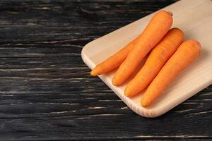 Fresh carrots on cutiing board with black wood background photo