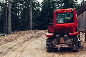 tractor bonnet and big wheels on natural soil road in spring forest photo