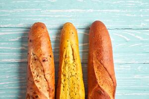 Three crispy french baguettes lie on an old wooden table with free space for text photo