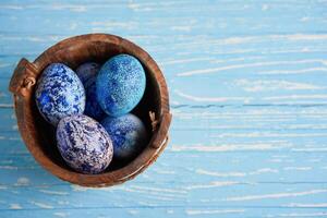 Blue cosmos chicken eggs lie in round wooden basket which stands on a blue wooden table. photo