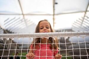 Little girl lean on net looking away photo