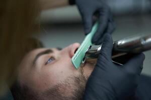 Young beautiful caucasian woman hairdresser cuts beard  handsome man at modern barbershop photo