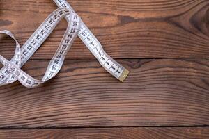 White measuring tape of a tailor lies in corner on dark wooden background. photo