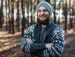 un joven hombre con un barba camina en un pino bosque. retrato de un brutal barbado hombre otoño bosque foto