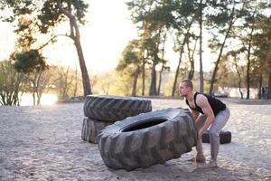 Strong man training workout lifting large tire outdoor DIY gym. photo