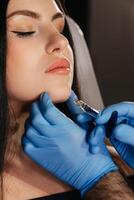 Closeup of young woman receiving injection in beauty salon. Cosmetology. Filler injection chin make chin longer photo