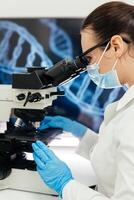 Medical Research Scientist Looks at Biological Samples Under Digital Microscope in Applied Science Laboratory. Beautiful Caucasian Lab Engineer in White Coat Working on Vaccine and Medicine photo