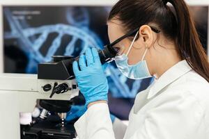 Medical Research Scientist Looks at Biological Samples Under Digital Microscope in Applied Science Laboratory. Beautiful Caucasian Lab Engineer in White Coat Working on Vaccine and Medicine photo