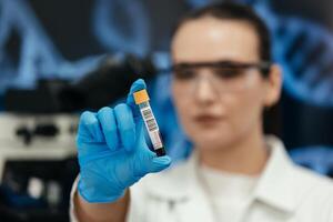 Doctor hand taking a blood sample tube from a rack with machines of analysis in the lab background, Technician holding blood tube test in the research laboratory photo