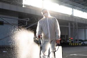 hombre vestido blanco protector mono pulverización superficie antibacteriano desinfectante rociador durante cuarentena foto