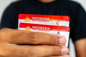 Jakarta, Indonesia, 2024 - A man in black clothes holding the Indonesia driving license for car and motorcycle photo