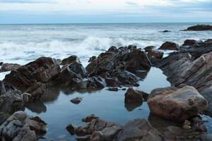 afilado Roca en el mar o Oceano espuma ola foto