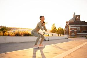 Sporty woman doing jumping squats exercises on stairs in park. Bodyweight training on sunset. photo