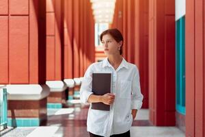 Businesswoman portrait. Caucasian female business person standing outdoor with business paper document holder. photo