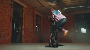 atlético mujer hace enroscarse formación rutina en hilado estacionario bicicleta en gimnasia, extensión ejercicios video