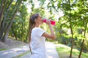 Woman drink water red bottle after morning workout. photo