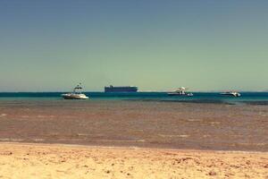 three boats and a tanker in the sea bay with clear water photo