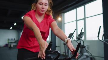 vrouw presteert aëroob uithoudingsvermogen opleiding training cardio routine- Aan de simulatoren, fiets opleiding video