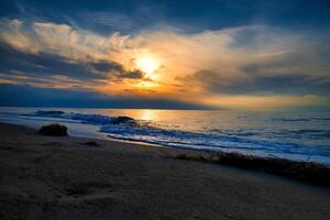 atardecer, iluminado mar. arenoso playa en el primer plano. ligero ondas. báltico mar foto