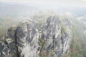 Jagged rocks at the Basteibridge. Wide view over trees and mountains. National park photo