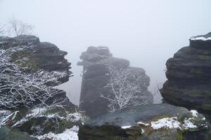 On the large Zschirnstein in fog. Rock covered with snow. Viewpoint Elbe Sandstone Mountains photo