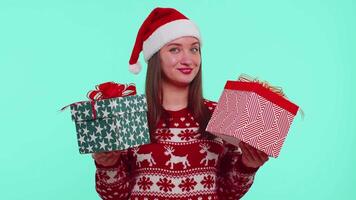 Joyful girl in red Christmas sweater presenting two Christmas gift boxes, shopping holiday sale eve video