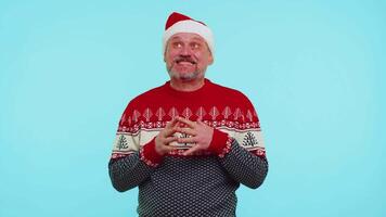 Cheerful man in sweater Santa Christmas hat getting present gift box, expressing amazement happiness video