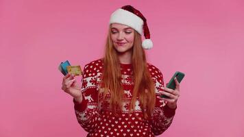 vrouw in Kerstmis trui gebruik mobiel cel telefoon en plastic credit bank kaart, winnen, kalibreren, Wauw video