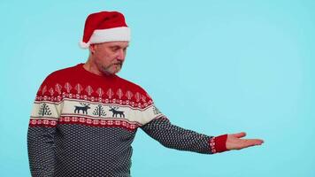 Man wears red Christmas deer sweater showing thumbs up and pointing at on blank advertisement space video