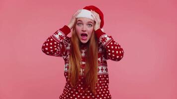 Teen adult girl in Christmas hat raising hands in surprise shocked by sudden victory, wow emotion video