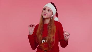 Woman in Christmas sweater listening music via earphones, dancing disco fooling around having fun video