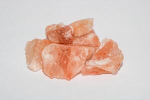 Pink himalayan salt pieces on isolated white background. Himalayan pink salt rocks on white background. photo