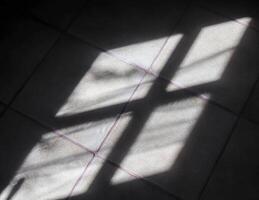 Abstract concept of soft shadows of the sunlight through a window on a tile background photo