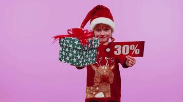 litet barn flicka i jul hatt som visar gåva lådor och 30 procent rabatt inskriptioner baner text video