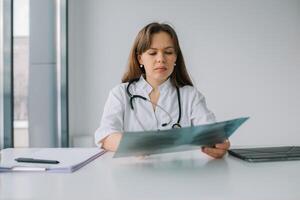 joven caucásico mujer médico vistiendo blanco médico Saco y estetoscopio sostiene el radiografía en el hospital. diagnóstico de tuberculosis foto