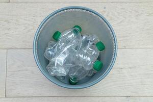 Different plastic bottles in the office trash can. Ecology and recycling of waste from various raw materials photo