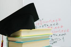 un negro cuadrado graduado sombrero con un rojo borla mentiras en un apilar de libros foto