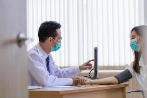 Doctor using sphygmomanometer checks blood pressure of a female patient, doctor checking blood pressure photo