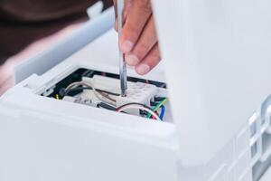 Technician man using a screwdriver to fix and install new air conditioner, repair service, and install new air conditioning concepts photo