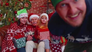 Man sets timer on mobile phone taking multigenerational family selfie portrait celebrating Christmas video