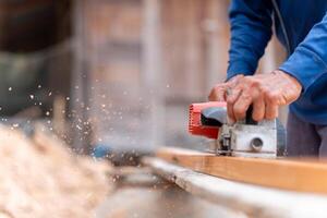 Carpenter man using electric planer to smooth out the wood, Woodworking machine, craftsman planing boards with electric tools photo