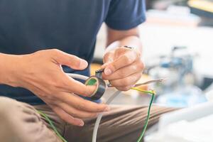 Technician man winds electrical tape around the wires to install new air conditioning, repairing servicing, and install new air conditioner concepts photo