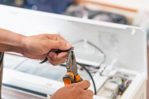 Technician man cutting electrical wires with pliers for install new air conditioning, repairing servicing and install new air conditioner concepts photo