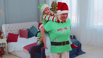 Grandmother carrying small girl toddler kid, playing piggyback ride game at home Christmas bedroom video