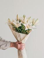 AI Generated Close-up of a hand holding a paper-wrapped bouquet of white lilies photo