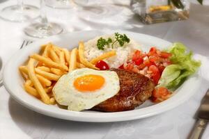 against horse steak with fries, egg, rice and vinaigrette sauce photo