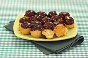 profiteroles stuffed and covered in chocolate sauce photo