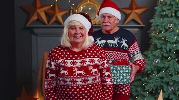 Grandfather covering eyes of old grandmother with surprise Christmas gift present box at home room video