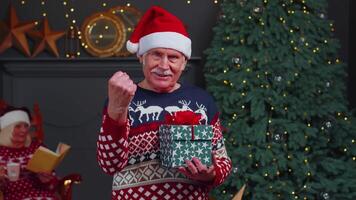 Senior grandfather in Christmas sweater celebrate success win scream doing winner hands gesture video